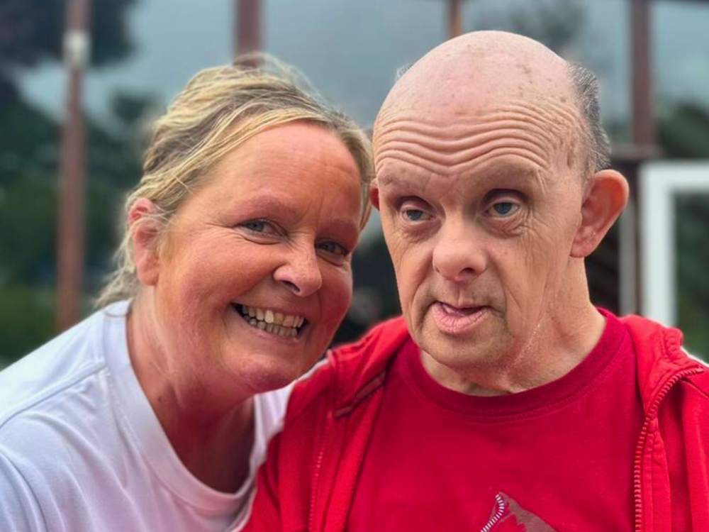 Elderly man and female helper smiling at camera