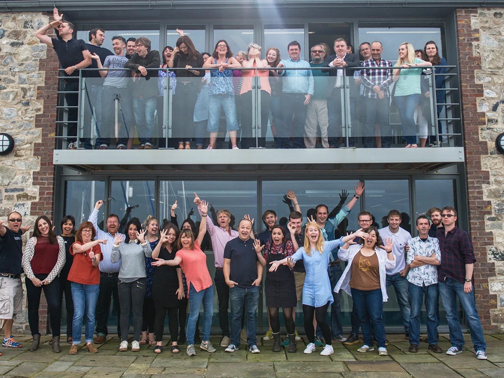 Large group of professionals smiling and waving to camera