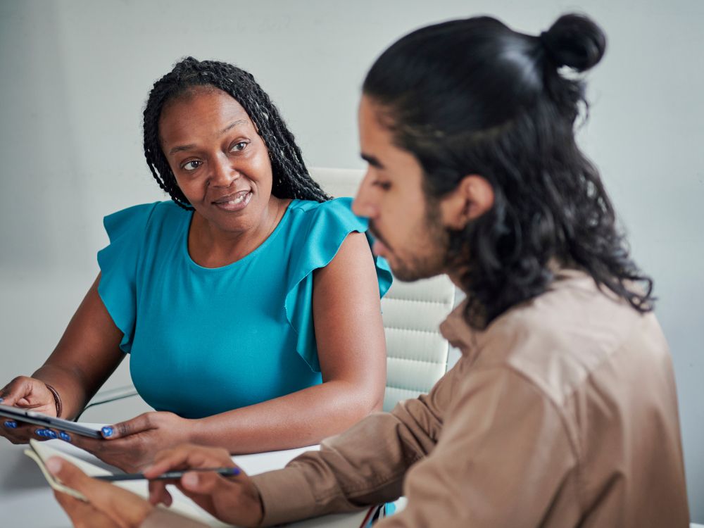 Woman coaching younger male colleague at work