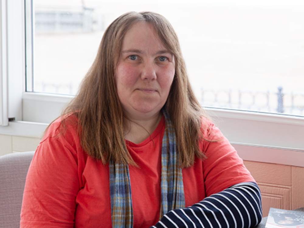 Woamn in red tshirt sitting at a table