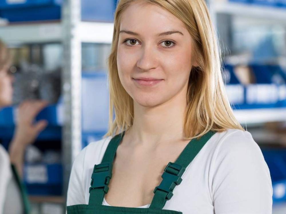 Young woman in green work apron smiling to camera
