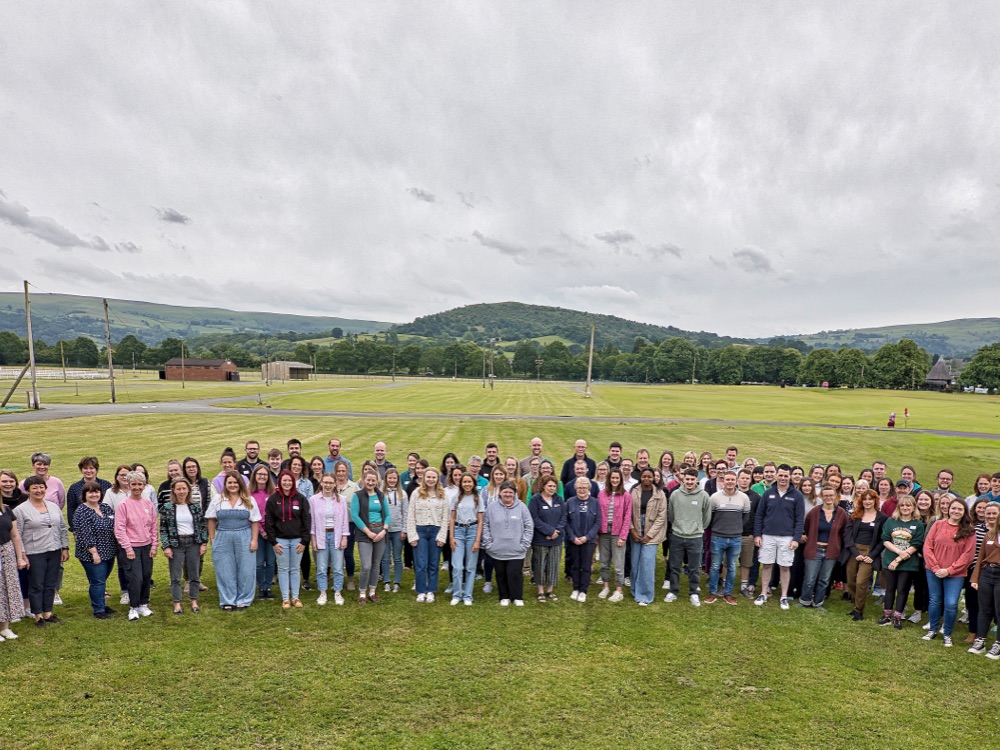 Large group of people standing on a playing field looking up at the camera