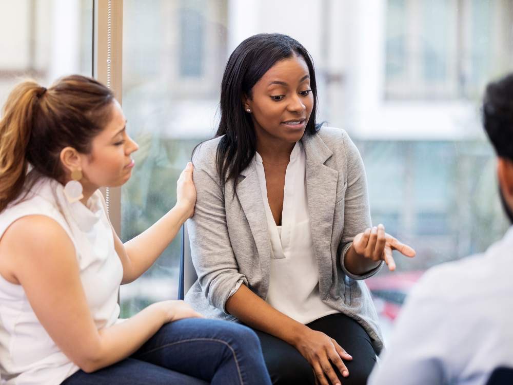 Woman talking at work and being comforted by female colleague