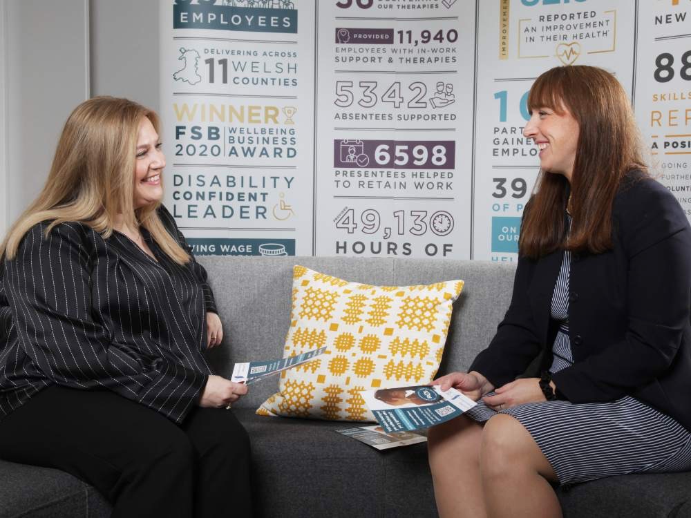 Two professional women talking on sofa at work