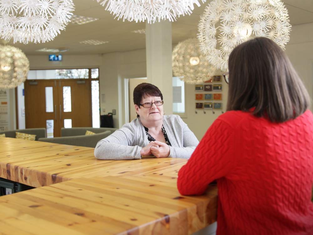 Two women talking at countertop in office breakout area