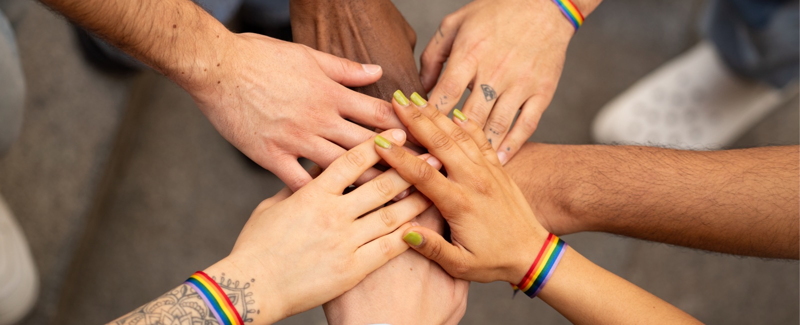 Seven hands with different skin colours overlaid and touching