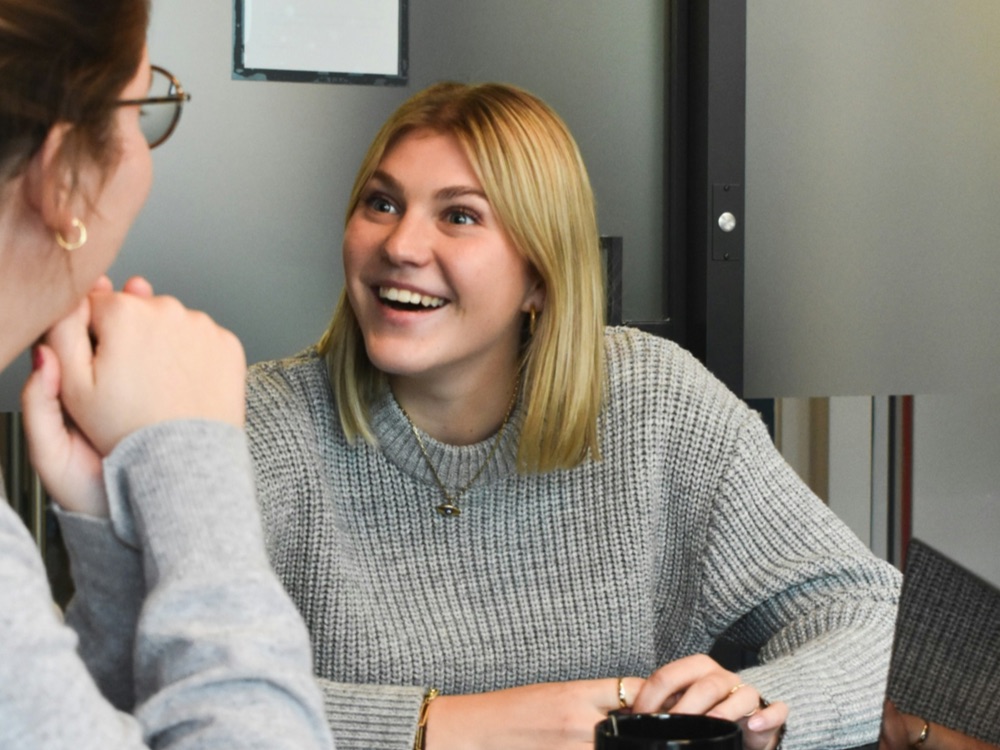 Two young women smiling and talking at work