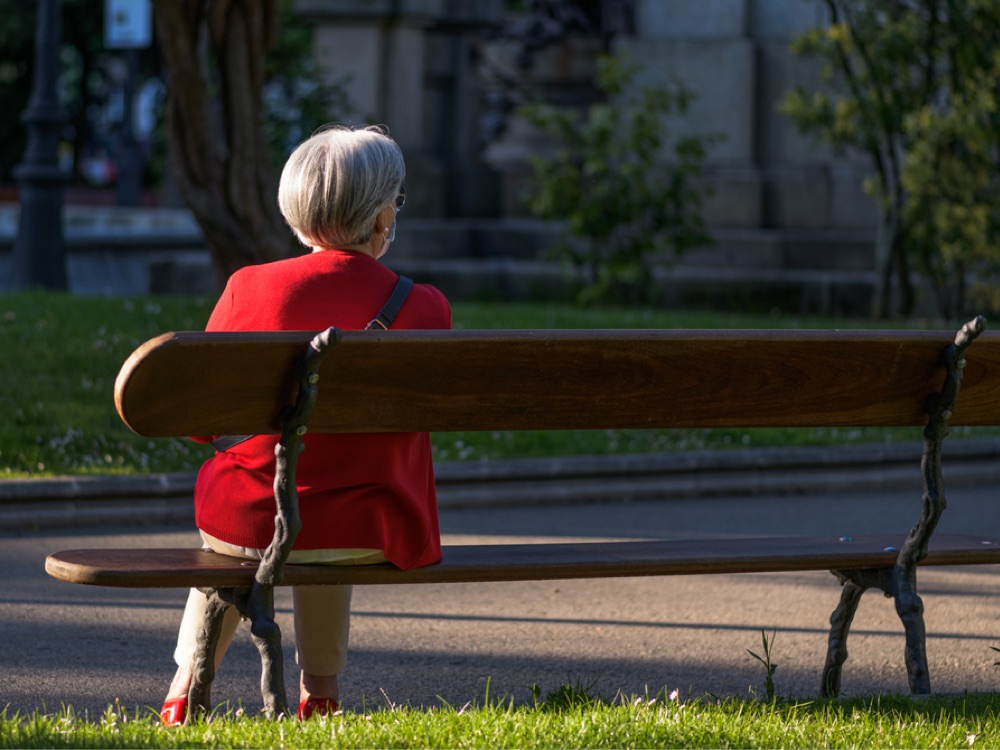 Smartly dressed mature woman sitting alone on park bench