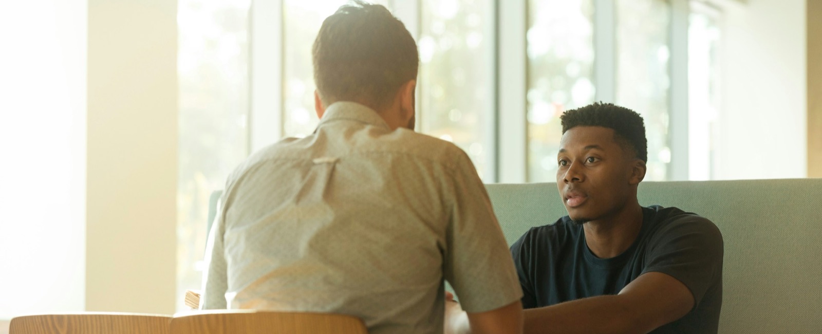 Young males sitting in bright office space face to face in discussion