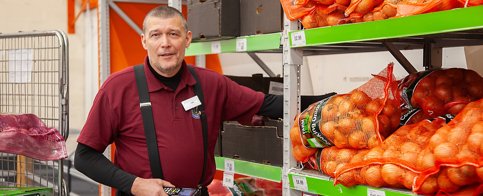 Mature male factory worker standing by shelves full of vegetables