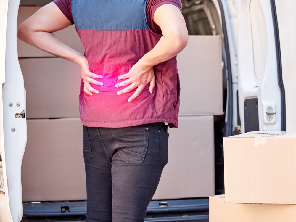 Man standing and holding his lower back in discomfort