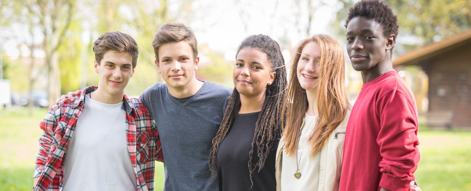 Five teenagers standing together outside smiling